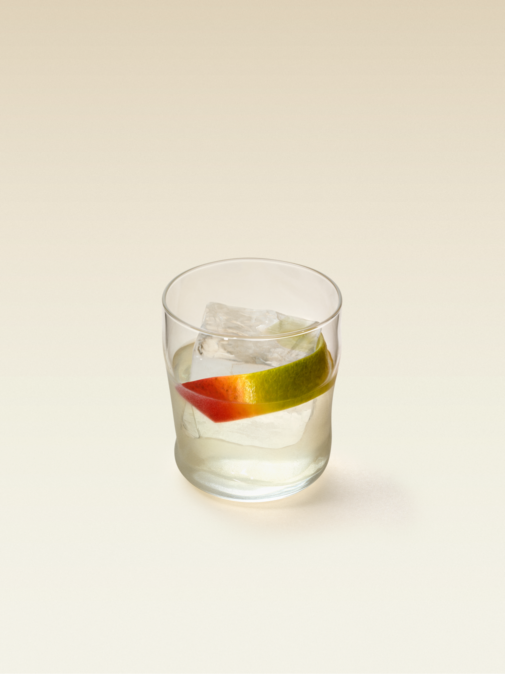 Cocktail glass with large rocks ice cube and slice of mango, displaying a mango negroni.